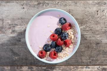 Healthy smoothie bowl with berries on wooden table. 