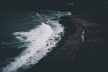 Dark, moody coastal scene. Waves crashing on a rocky shore