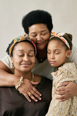 Three multigenerational African American women embracing with closed eyes, radiating love and serenity Family members sharing a tender moment of connection and affection