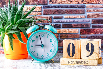 Wooden calendar with the date November 9.Monthly calendar for planning and management concept with alarm clock on wooden background