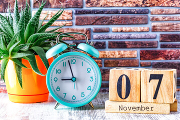 Wooden calendar with the date November 7.Monthly calendar for planning and management concept with alarm clock on wooden background