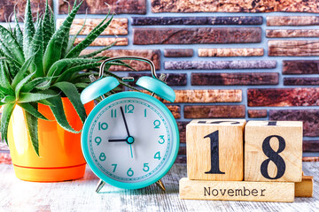 Wooden calendar with the date November 18.Monthly calendar for planning and management concept with alarm clock on wooden background
