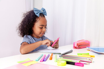 schoolgirl, ethnic sitting at a table with school supplies using a calculator
