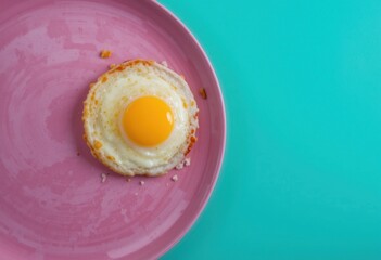 Huevo frito con yema perfectamente redonda en un plato rosa, colocado sobre un fondo verde azulado brillante, escena gastronómica minimalista