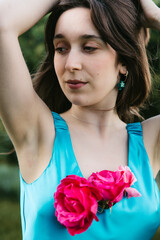 Close-up portrait of young woman with roses on turquoise dress in garden