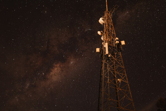 Telecommunications tower illuminated at night with Milky Way