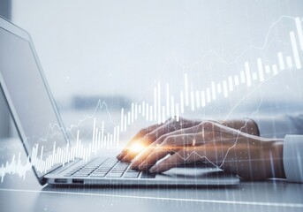 A persons hands typing on a laptop with a stock market graph overlay