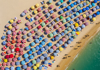 Fototapeta premium Vibrant summer escape awaits with a colorful aerial view of beach umbrellas and turquoise waters, perfect for travel brochures and vacation promotions