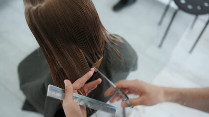 Professional Hairdresser Cutting A Little Girl's Hair With Scissors