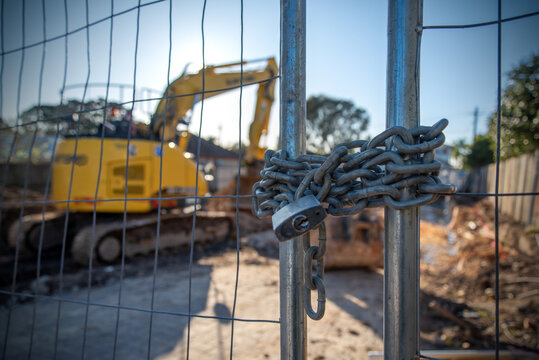 A locked gate with chain at a construction site with machinery in the background