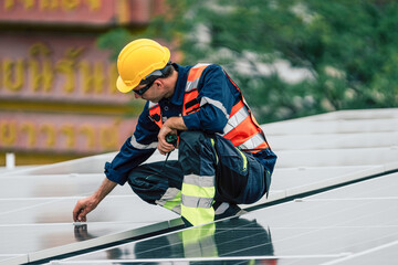 Skilled technician installs solar panels on a building rooftop during daytime in an urban...
