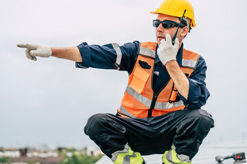 Construction worker directing operations on a rooftop with a radio in hand during an overcast day