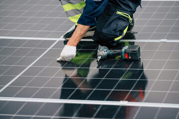 Technician installing solar panels on a rooftop during daytime with tools in hand and safety gear on