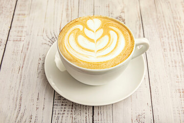 White ceramic cup with a  design in the foam, illuminated by natural side lighting