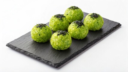 Several matcha onigiri rice balls with sesame seeds are on a slate plate