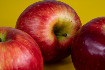 foto de tres manzanas rojas sobre fondo amarillo y bordes difuminados 