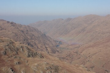High-angle view of a valley, mountains, and rainbow