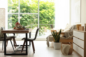 Wooden table, chairs, sofa and decor in dining room. Interior design