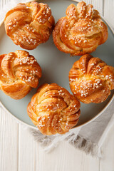 Freshly baked Knot sugar buns with vanilla close-up in a plate on the table. Vertical top view from above
