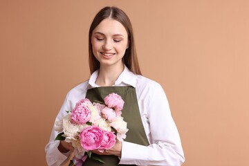 Florist with beautiful bouquet of peonies on dark beige background