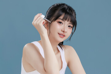 Fototapeta premium Portrait of cute Asian teen woman hold dropper apply serum on face smile attractive isolated on beige background.