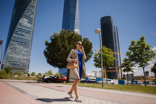 Businesswoman walking and talking on phone in madrid, spain