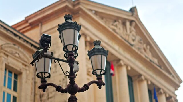 Close up of a street lamp with a blurred view of the Nice courthouse on the background