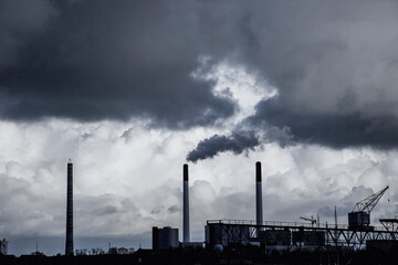 Industrial skyline in London with smoking chimneys under dramatic clouds, representing pollution, energy production and urban environmental challenges in contemporary cityscape.