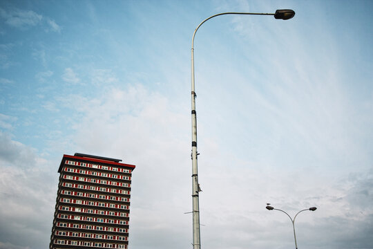 Low-angle view of streetlamps and residential tower against blue sky, expressing visual geometry, verticality and urban infrastructure in contemporary development zones.