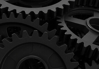 A close up black and white image showing multiple interlocking gears and their intricate teeth