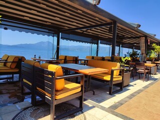 Beautiful horizontal photography concept image picture of a restaurant with tables by the sea view with blue sky golden sand sunlight summer vibes vacation palm trees wallpaper ultra high hd quality 