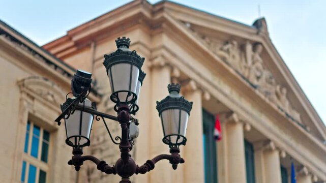 Close up of a street lamp with a blurred view of the Nice courthouse on the background