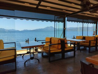 Beautiful horizontal photography concept image picture of a restaurant with tables by the sea view with blue sky golden sand sunlight summer vibes vacation palm trees wallpaper ultra high hd quality 