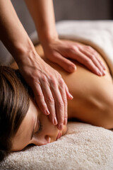 Close-up of hands massaging a woman's back in a spa setting.