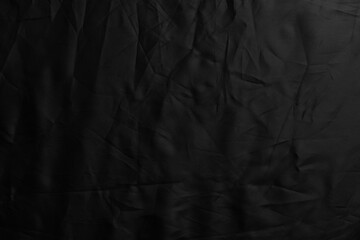 Black crumpled material surface of dark synthetic fabric. Abstract wrinkled background