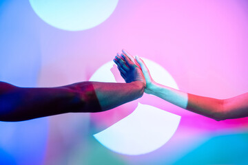 Multiethnic hands joining against colorful background