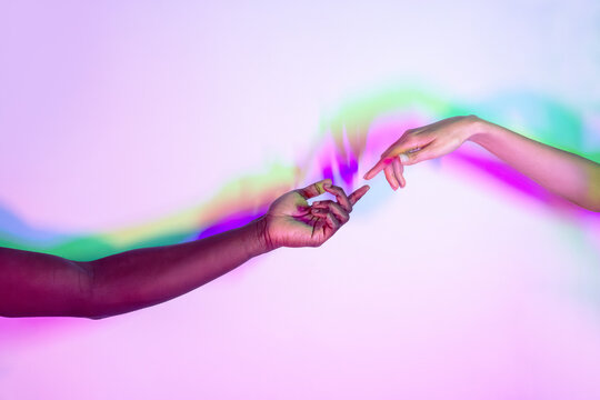 Multiethnic hands reaching in colorful light background - Powered by Adobe