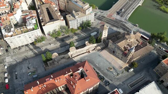 Aerial view of the old buildings with red rooftops contrasting with the bridge over the river, Zaragoza, Aragon, Spain.