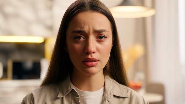 Close-up portrait of young Caucasian woman with tearful eyes sad expression emotional bad negative mood face at home sorrow mental health struggle pain stress frustrated upset fail depressed emotion