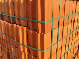 Photo image close up of stack of red bricks outdoor on wooden pallets on construction building site...
