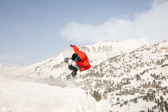 Snowboarder performing freeride jump in snowy mountains