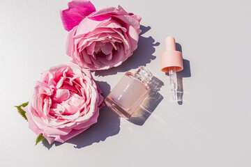 Rose water and serum with pink blossoms on white background