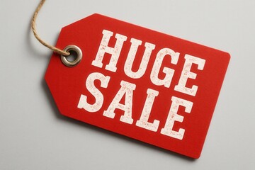 A red sale tag with the words "HUGE SALE" printed in bold white letters, featuring a grommet and rope for hanging, ideal for promotions and retail advertising.