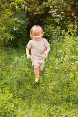 Little boy running barefoot through the green grass
