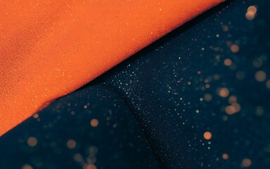 Textured orange fabric meets deep blue fabric with glitter and bokeh abstract background image