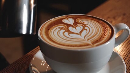 A barista finishes pouring milk into a cup of coffee, forming a heart shape in the foam. A moment of latte art, showcasing the skill and culture of coffee. Lifestyle, gastronomy, and cozy moments.