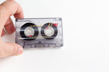 Hand holding old worn audio cassette on white background close-up, mockup, old audio cassette as a symbol of retro music