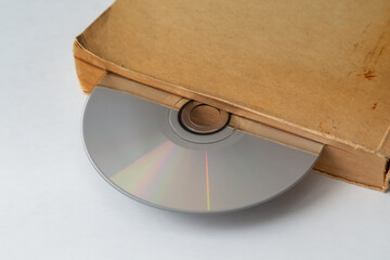 Compact disc in old worn book as if in a drive, CD as a bookmark in an old book, digitizing archives and old data, old and new technologies.