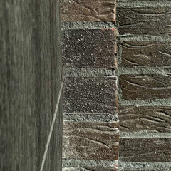 Close-up of textured entrance door and brick wall transition with vertical corner detail