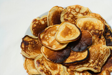 Golden homemade sweet pancakes on white plate